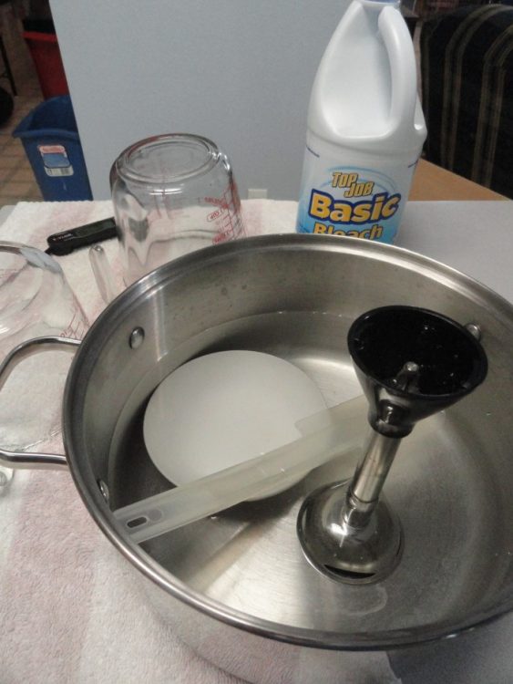 Lotion-making tools sitting in a disinfecting solution
